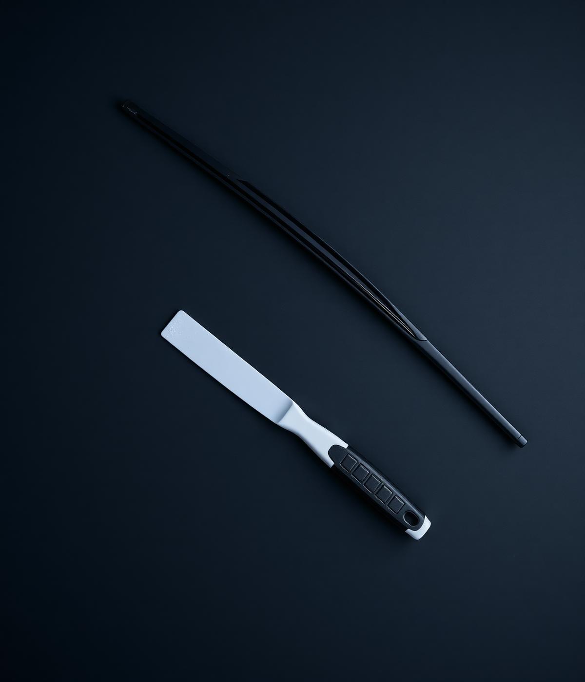 Wiper blade and ice scraper laid on a dark surface